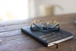 black and brown eyeglasses on book on brown wooden table by carolyn christine courtesy of Unsplash.