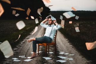 man sitting on chair with book by Dmitry Ratushny courtesy of Unsplash.