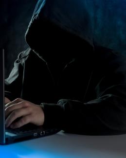 a man in a hoodie using a laptop computer by Bermix Studio courtesy of Unsplash.